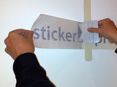 Een rakel drukt de eerste helft van de belettering aan