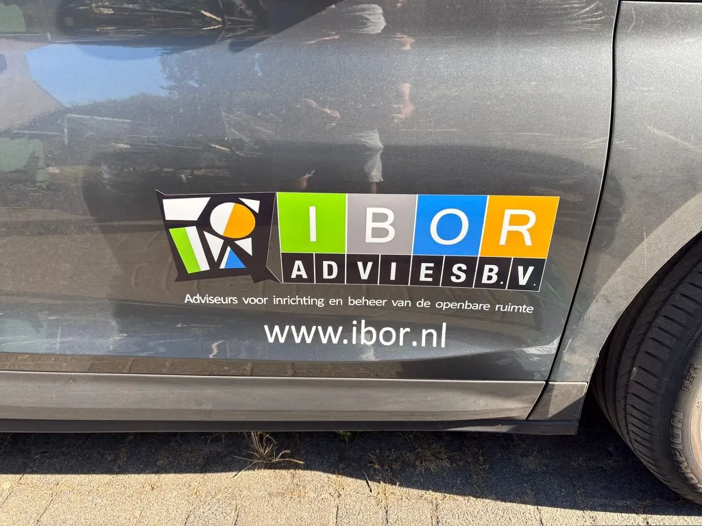 Grijze auto met het logo van IBOR Advies bv en de website op het portier