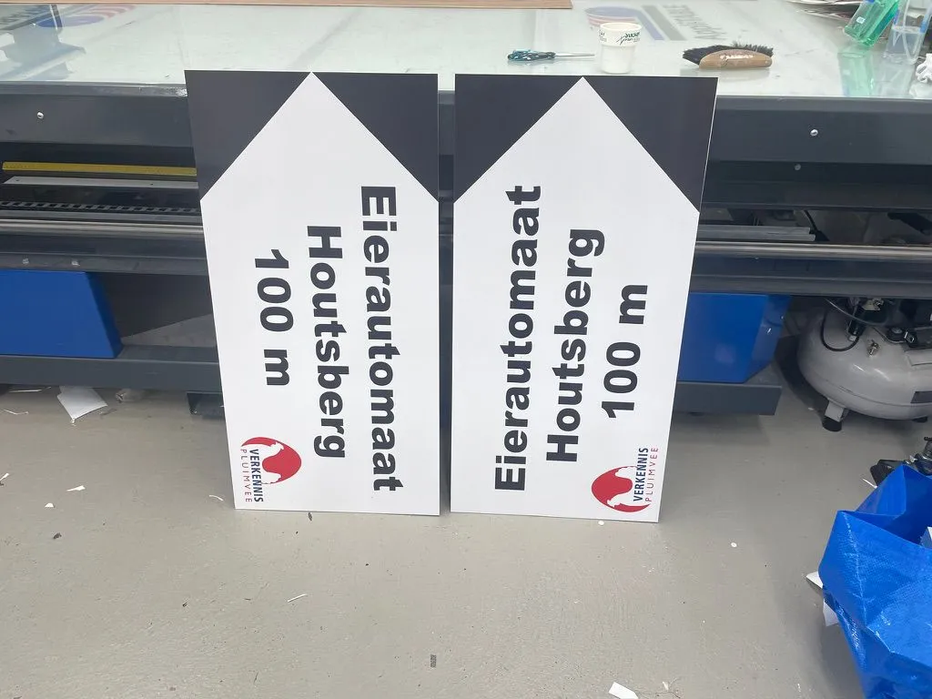 Twee pijlborden naar een eierautomaat op 100 meter
