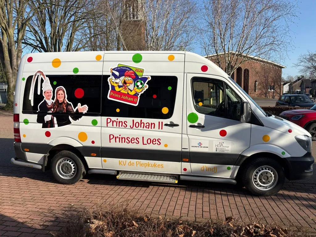 Witte bus beplakt met het prinsenpaar, confetti en de naam van de carnavalsvereniging