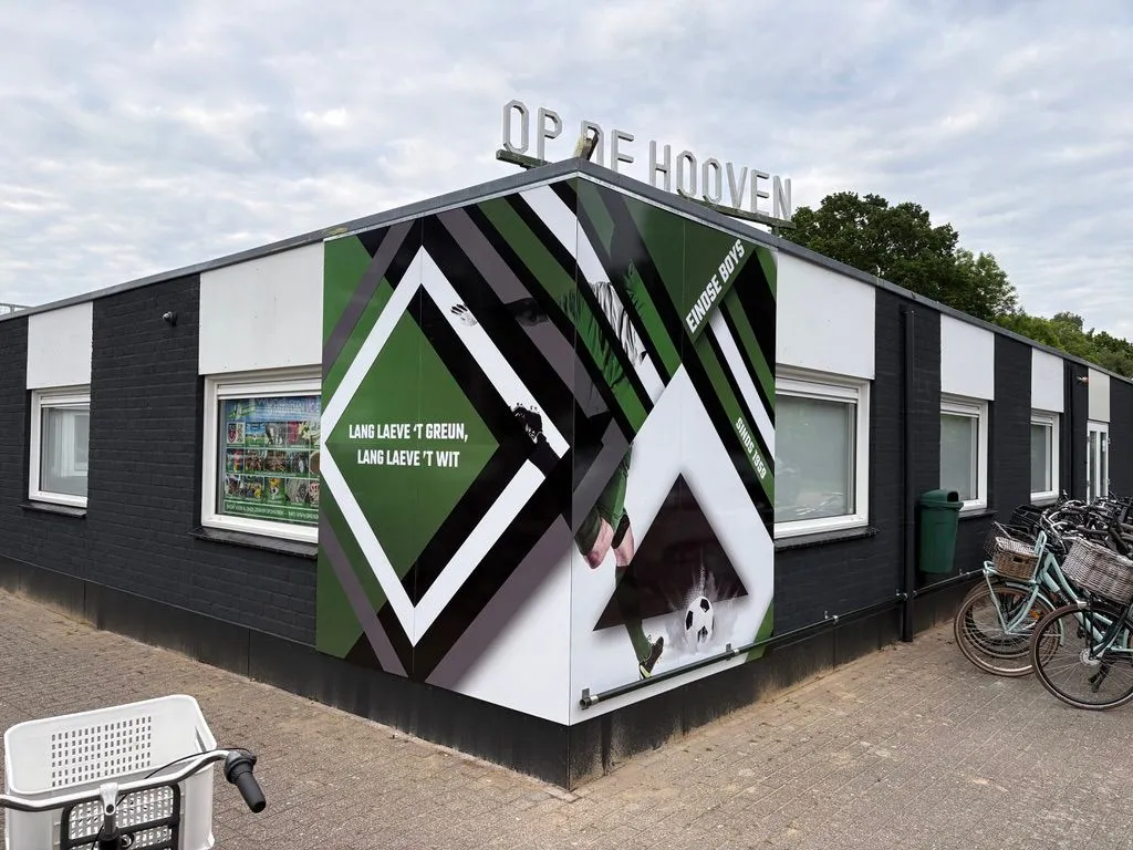 Clubhuis van sportpark Op de Hooven, rondom beplakt met een groen-wit ontwerp