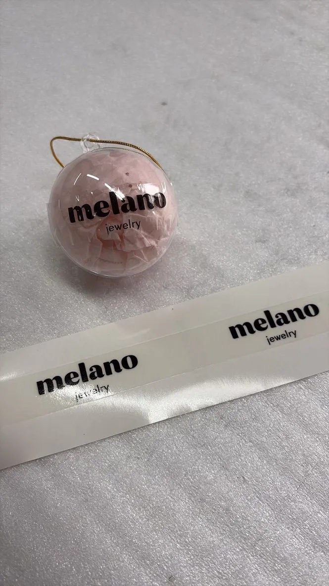 Roze verpakking met de productsticker van Melano Jewelry