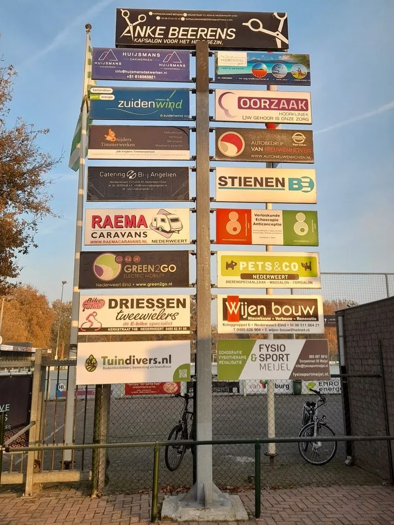 Paal met een rij sponsorbordjes van bedrijven uit de buurt